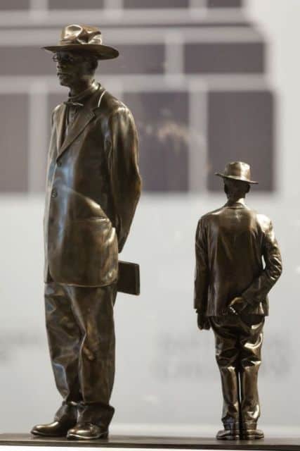 Statues of two bronze men dressed in formal attire, wearing hats, at the Inside the AAI Gala event.