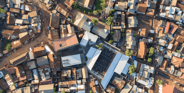 Aerial view of a luxury hotel and sports complex in a dense African cityscape.