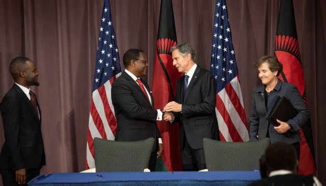 African leaders and US officials shaking hands at a formal event with flags in the background.