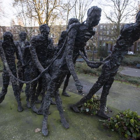 Bronze sculpture of people forming a human chain in an outdoor park.