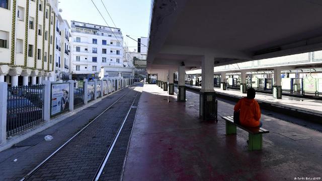 Urban train station platform in Africa with a solitary person sitting on a bench.