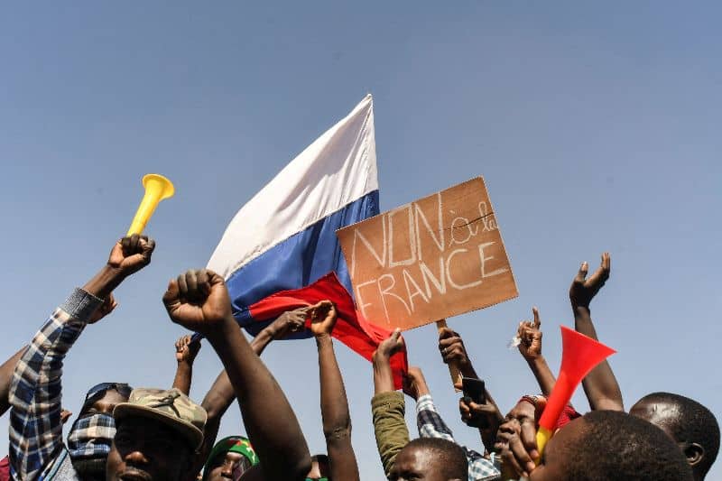 Crowd holding flags and signs during a lively demonstration in Africa.