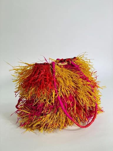 Colorful feathered handbag with pink accents, showcasing innovative design by emerging creatives.