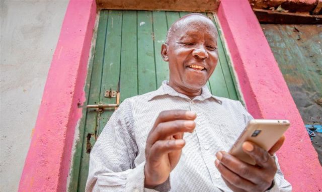 Farmer smiling while using a smartphone outdoors in Morocco, highlighting sustainable farming practi.