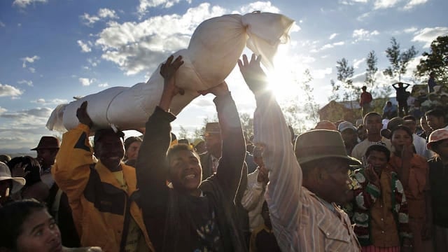 An image of Malagasy people celebrating the Day of the Dead with traditional offerings and vibrant c.