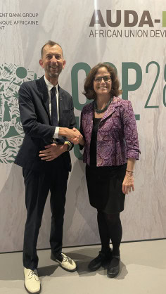 Two professionals shaking hands at COP28 Africa conference event.
