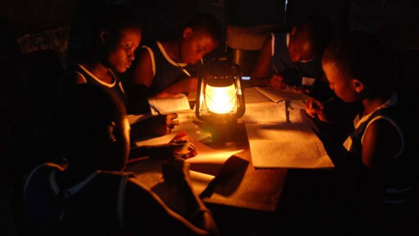 Children studying with lantern in a dark environment, emphasizing energy access challenges in Africa.