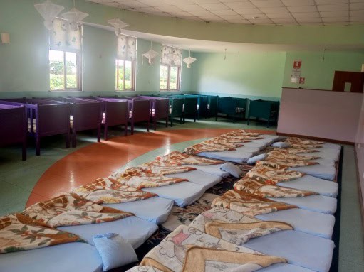 African women sleeping on mats in a community center.