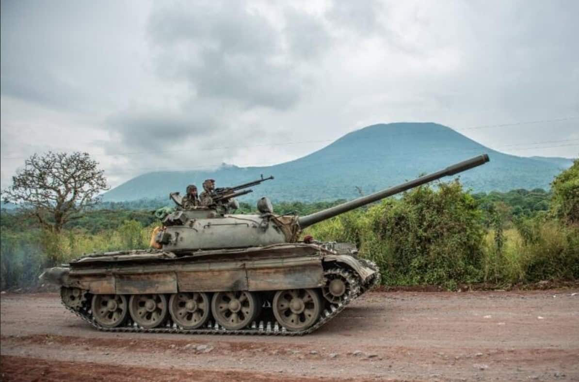 Tank in rural African landscape with mountains, representing history and conflict.