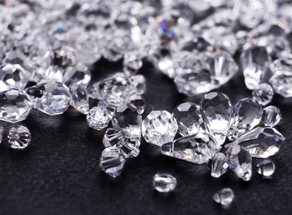 Diamond gemstones with sparkling facets on dark surface.