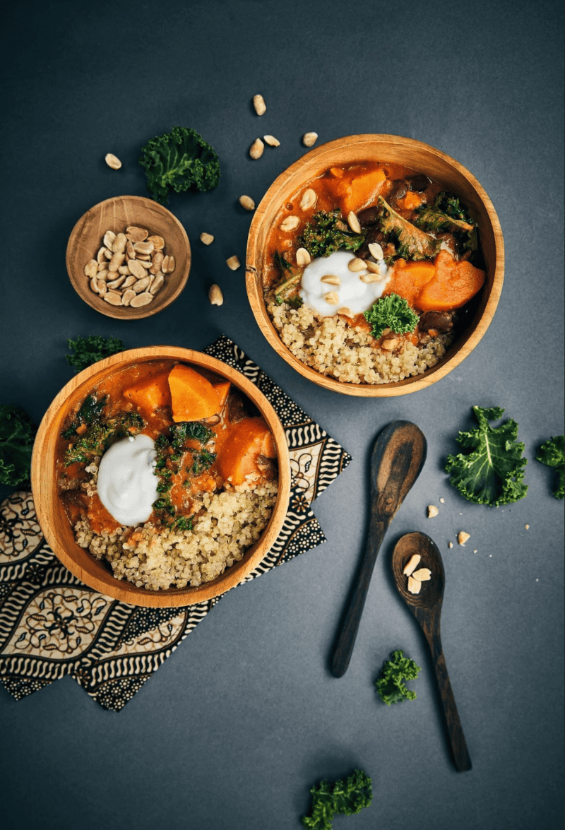 Vegetarian Moroccan vegetable stew served with quinoa, garnished with fresh herbs and yogurt.