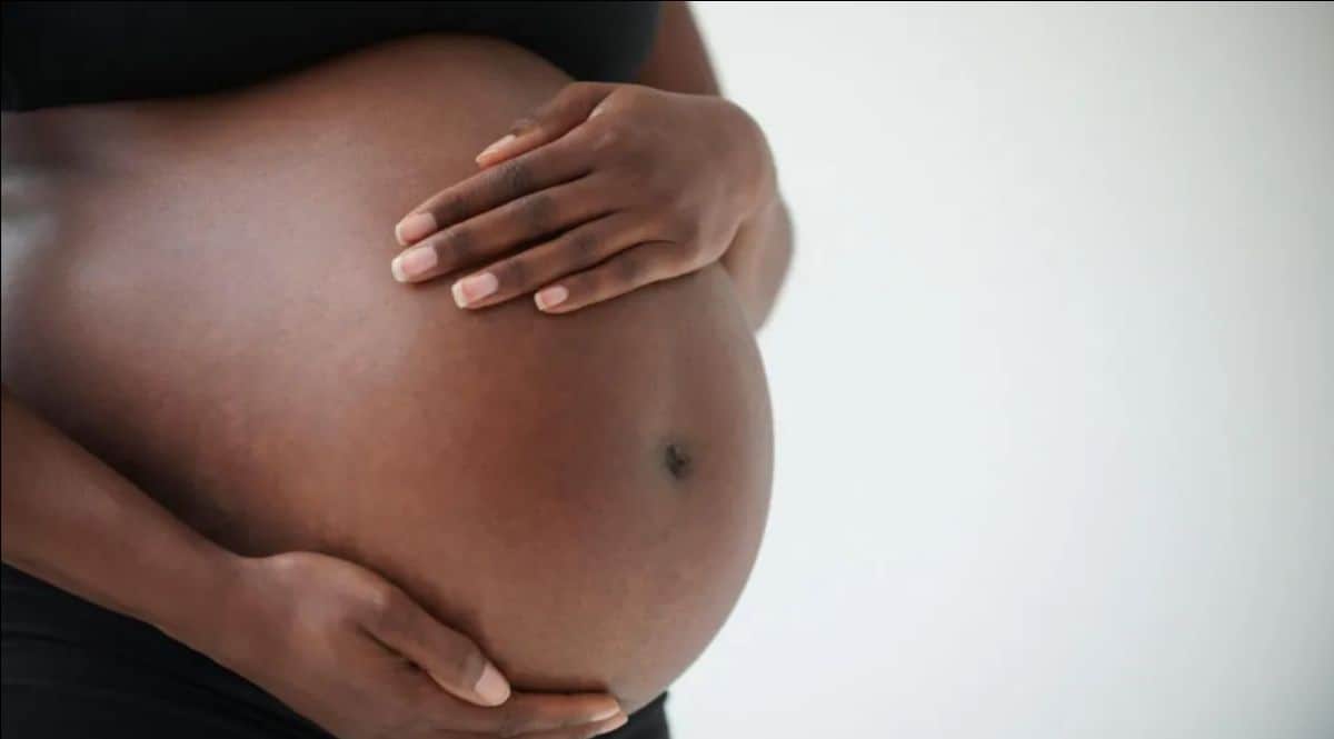 Pregnant woman holding her belly, symbolizing motherhood and African cultural heritage.