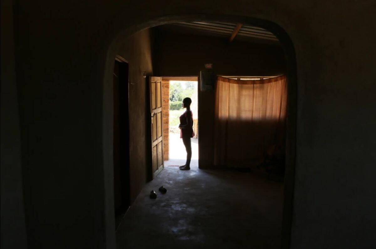 Silhouette of a woman standing in a doorway, backlit by natural light, highlighting African culture.