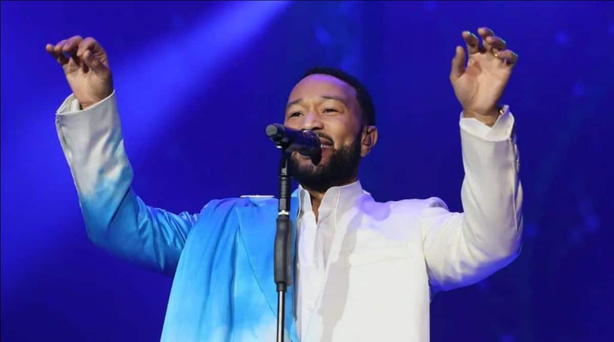 Performer singing passionately during a live concert in vibrant blue lighting.