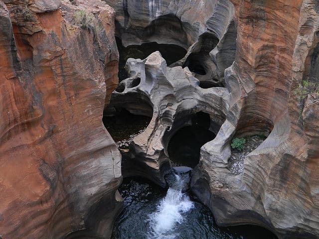 Ancient rock formations with unique shapes and a small waterfall in a canyon in Africa.