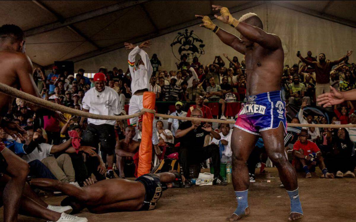 Tanzanian boxer in ring during a lively match with crowd cheering.