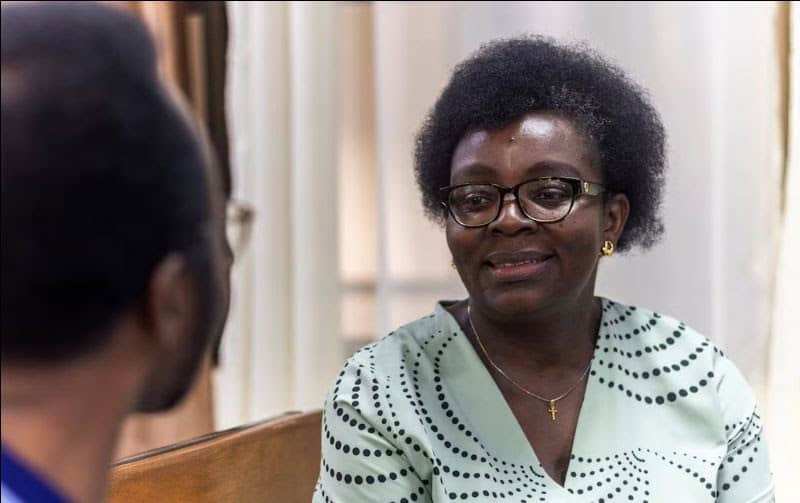 Nigerian woman speaking about health testing kits in an office setting.