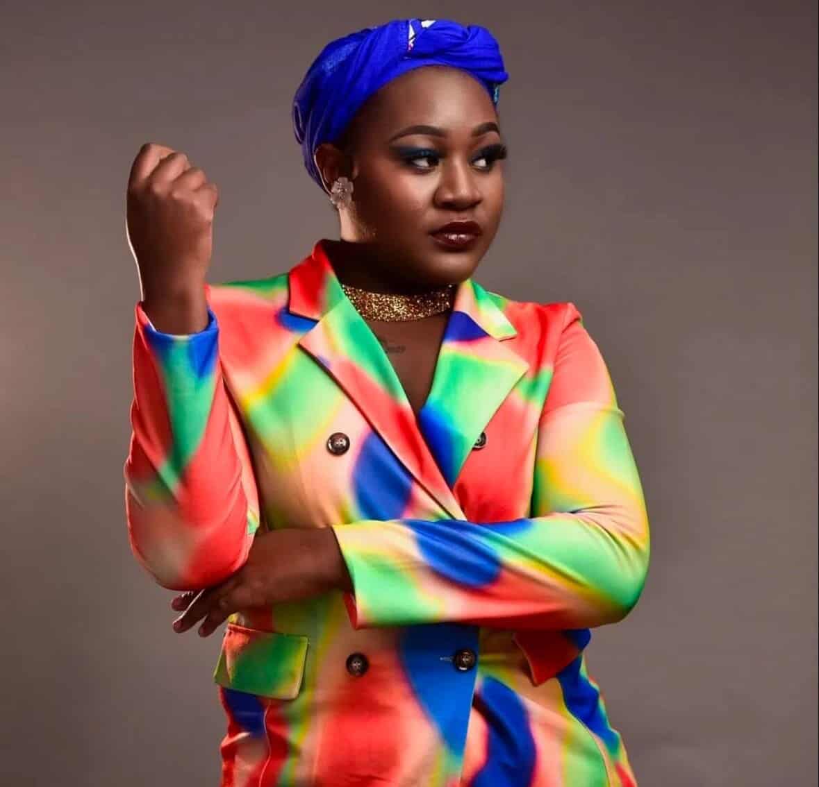 Portrait of Connie Chiume wearing colorful blazer and blue headwrap, celebrating youth storytelling.