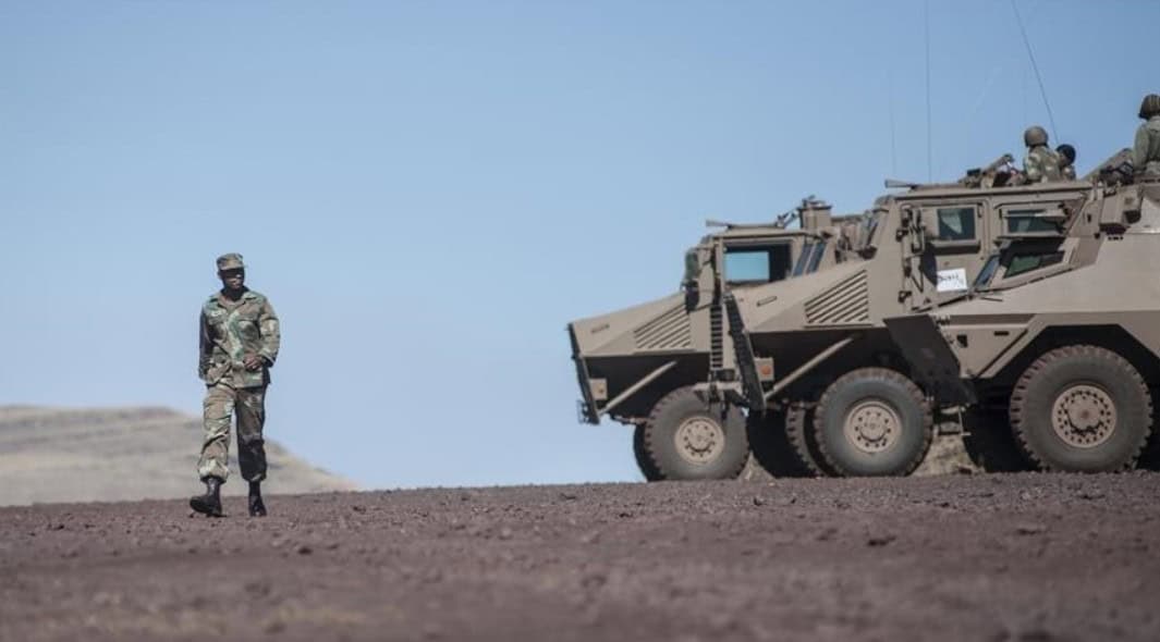 Military vehicle and soldier at Guinea-Sierra Leone border standoff.