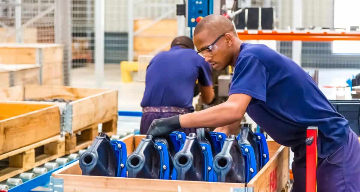 Young African workers assembling machinery in a modern factory.