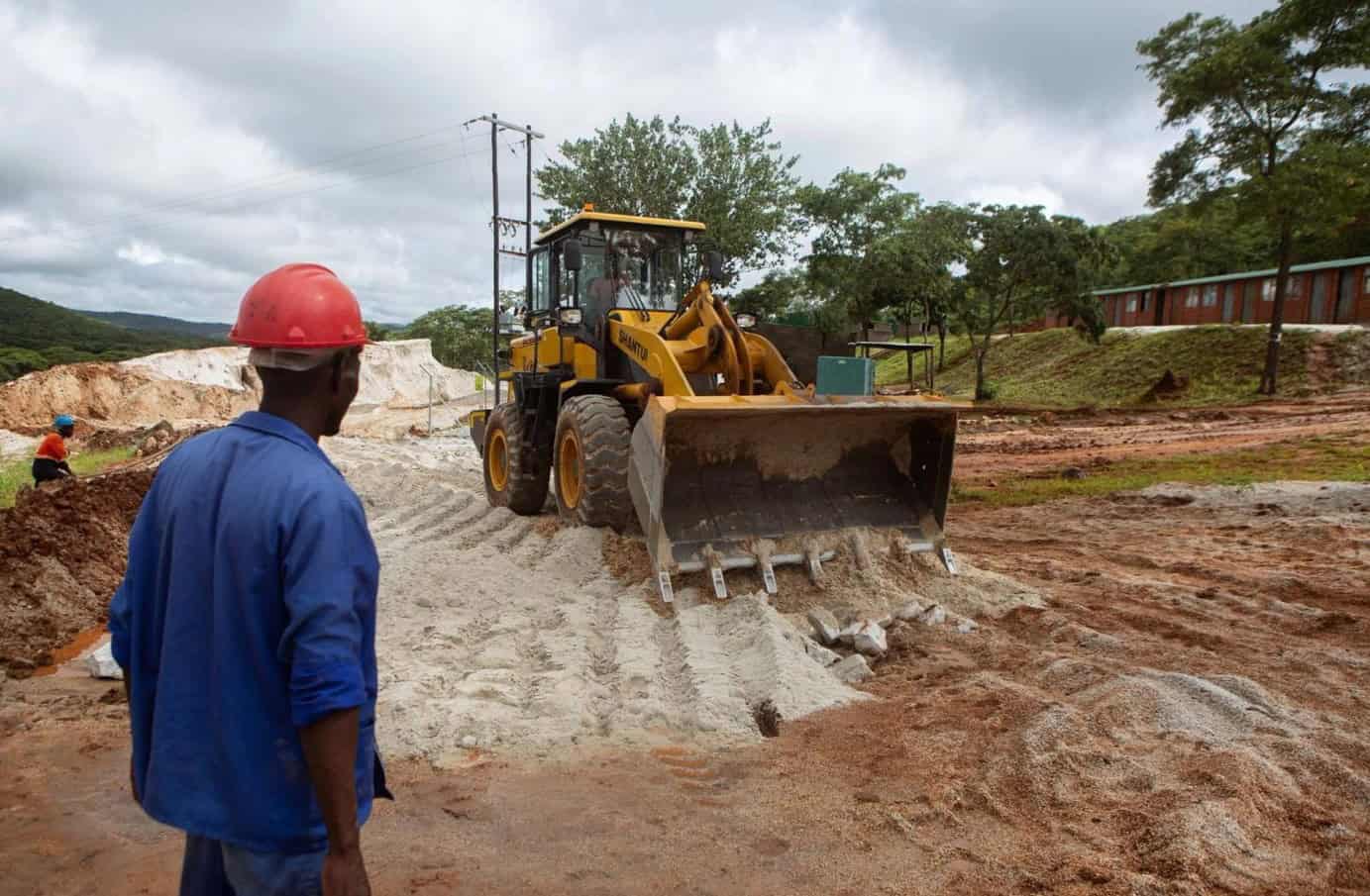 Construction worker monitoring bulldozer on construction site in Africa.