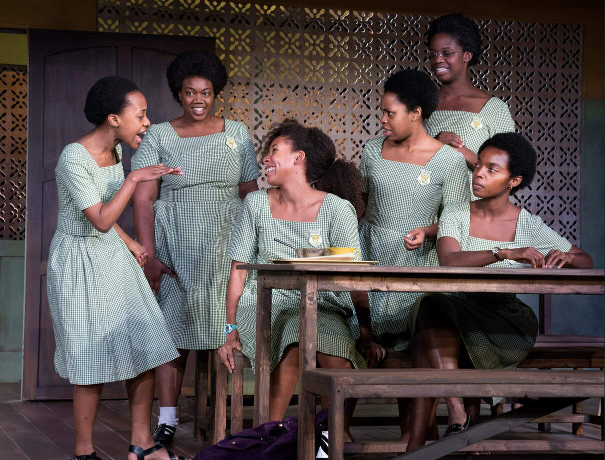 African women engaging in lively conversation at a social gathering.