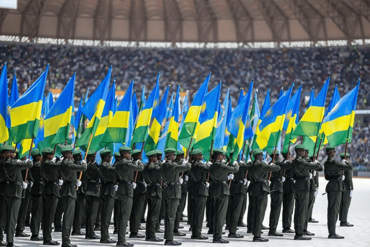 Rwandan soldiers in uniform holding flags during a military parade.