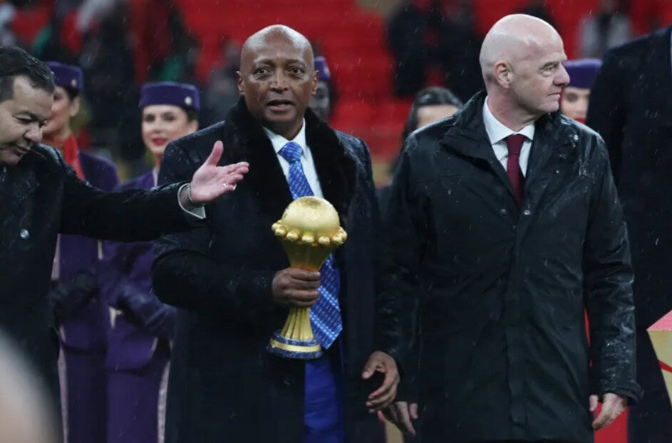 African football players and officials at an award ceremony, holding a trophy.