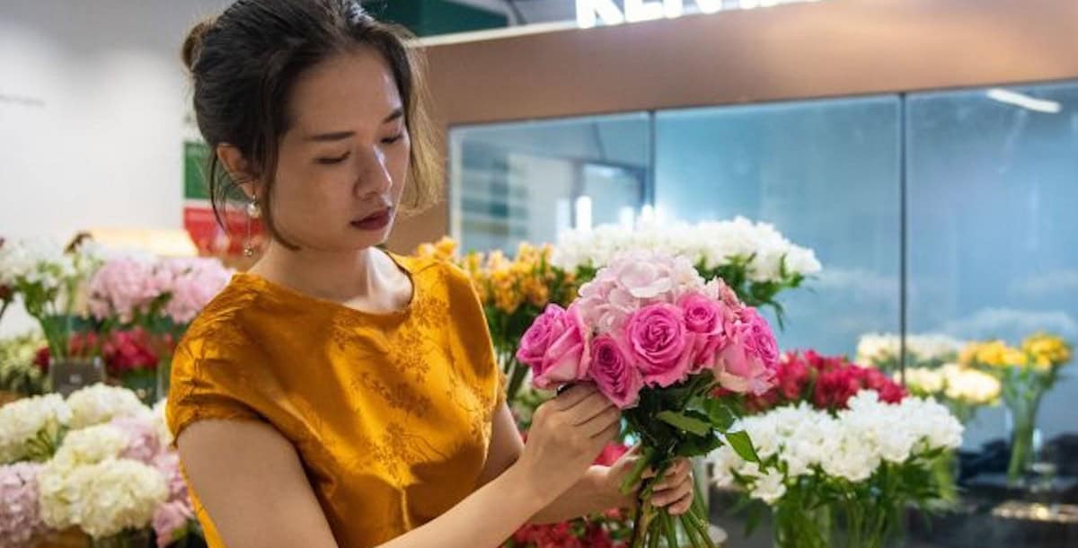 Beautiful woman selecting pink roses and white flowers at a flower market.