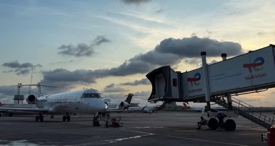 Airplane on tarmac at an African airport with a sunset sky in the background.
