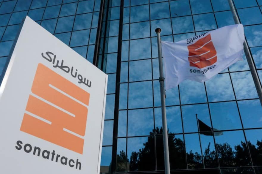 Modern office building with Sonatrach sign and flags in front.