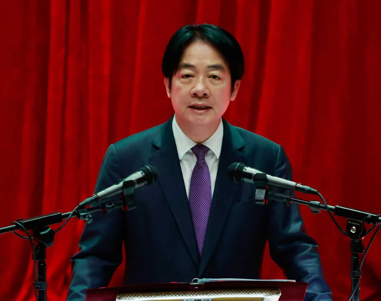 African leader delivering speech at a formal event with microphones.