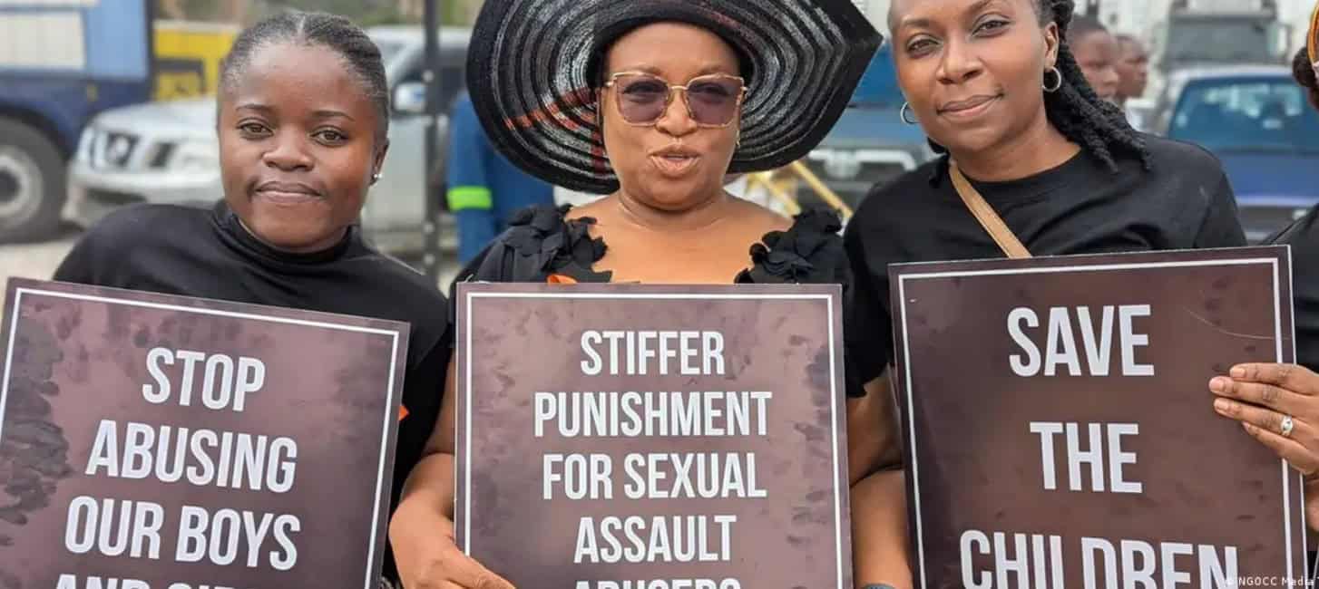 Women protesting child abuse with signs advocating for children's safety and justice.