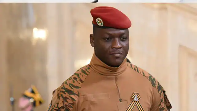 Burkinabe soldier in uniform with red beret, serious expression.