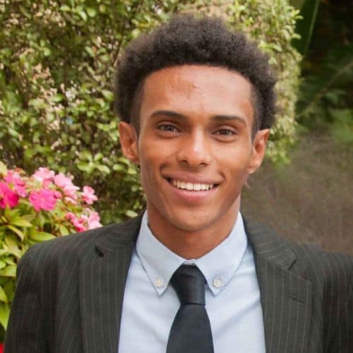 Young professional man smiling outdoors in a suit.