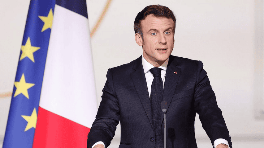 French President Macron speaking at a conference with African flags in the background.
