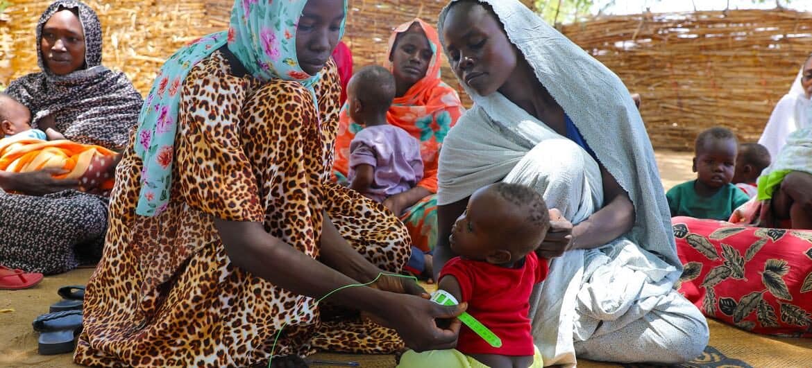 African community women and children engaging in a cultural gathering.